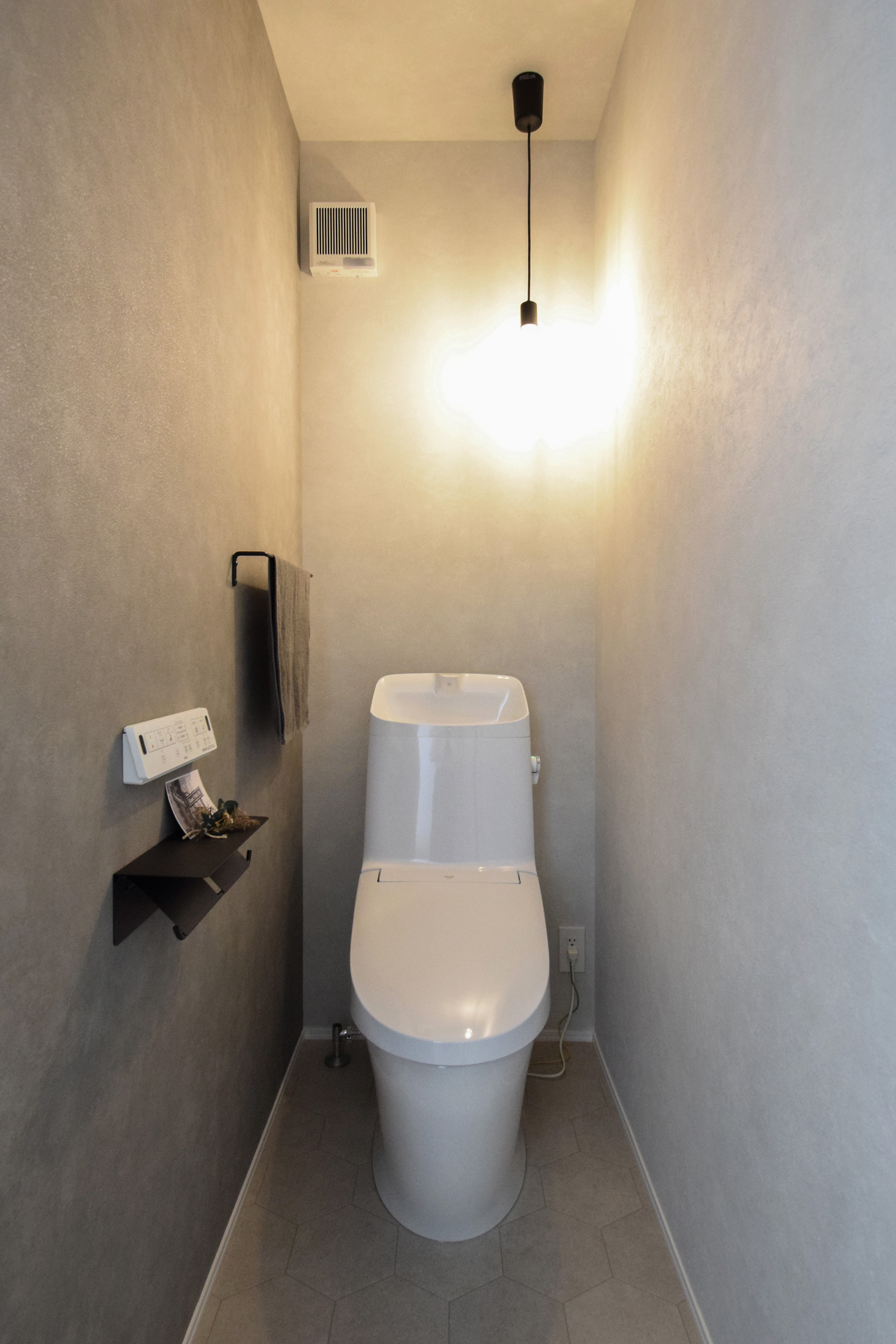 グレーのアクセントクロスとペンダント照明が映えるトイレ空間