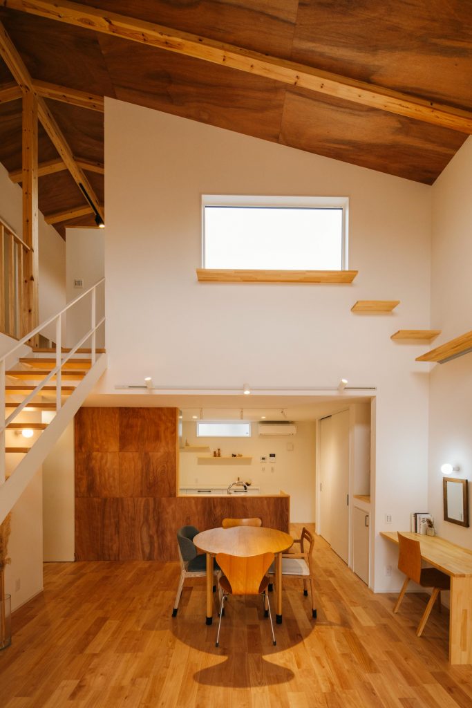 木のあたたかみに包まれたLDK空間。吹き抜け勾配天井やキッチン、無垢床、造作キャットウォークも木で統一。