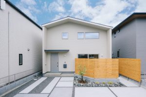 白いサイディング外壁に木目フェンスが映えるナチュラルデザインの新築注文住宅外観