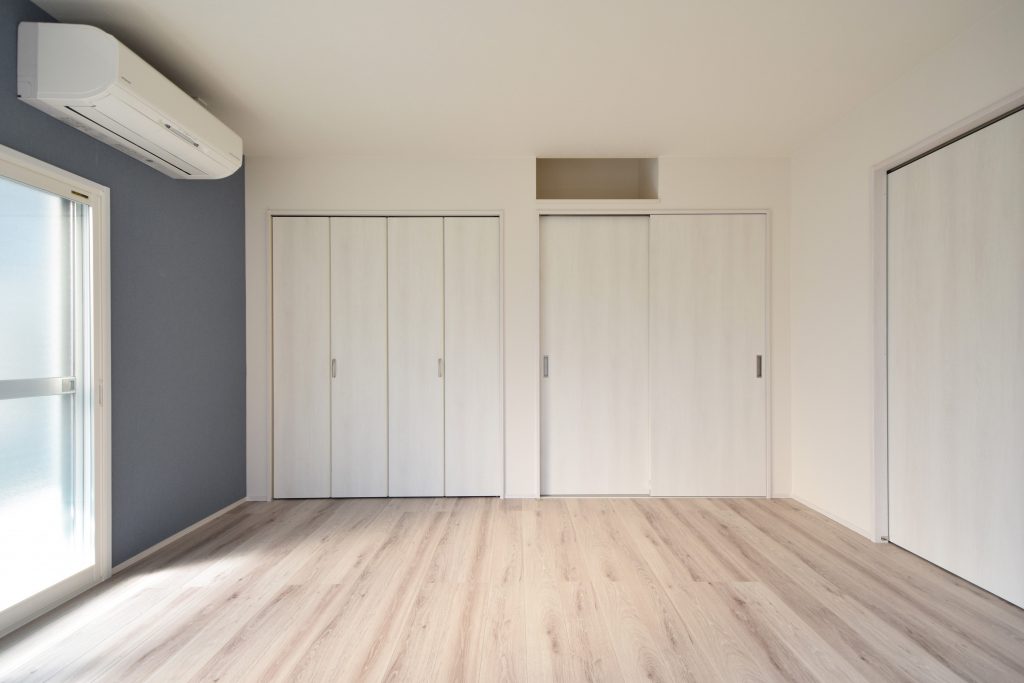 明るい木目調の床とアクセントクロスを採用したリフォーム後のリビング