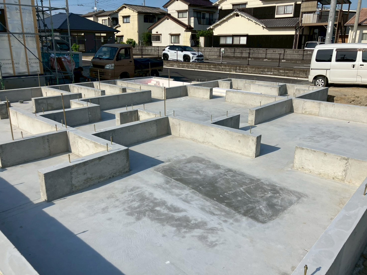 住宅の基礎工事中の様子。コンクリート基礎と足場が見える現場写真
