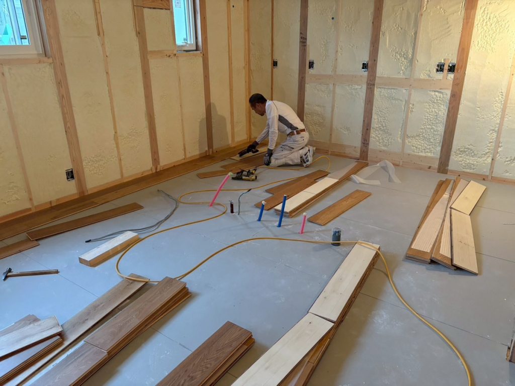 新築注文住宅の床材を一枚ずつ丁寧に施工している内装工事の様子