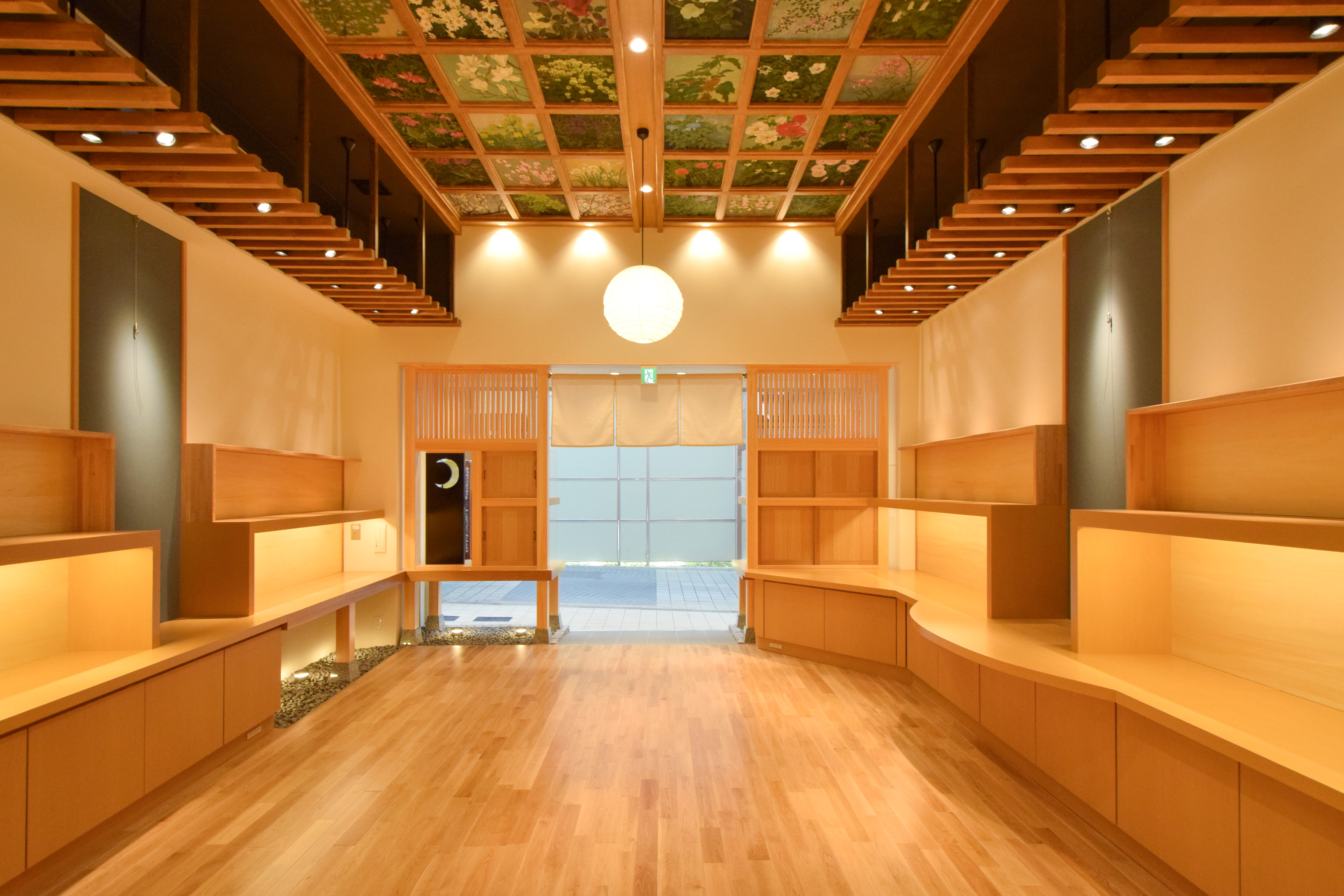 高天井と暖色照明が演出する開放的な木彫り人形店の内観